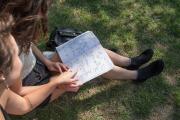 Students sitting outside in the grass looking down at their notebooks