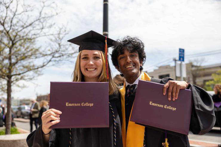 Two students holding their diplomas