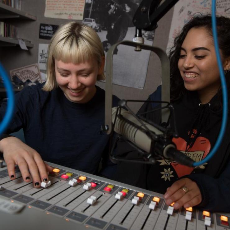 Two female undergraduate students work at the WERS radio station control board.