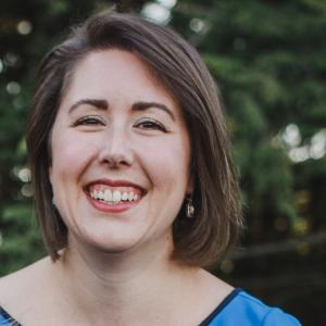 Image of Liz Chase, Senior Associate Director, Academic Assessment. Liz is facing the camera and smiling, wearing a blue dress.