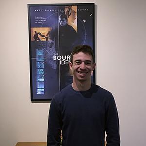 Student intern in front of poster at Captivate Entertainment