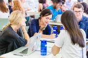 Students sitting around a table in discussion with laptops and notebooks