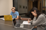 Two students working on laptops in meeting room