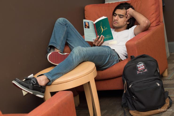student reading a book on a couch