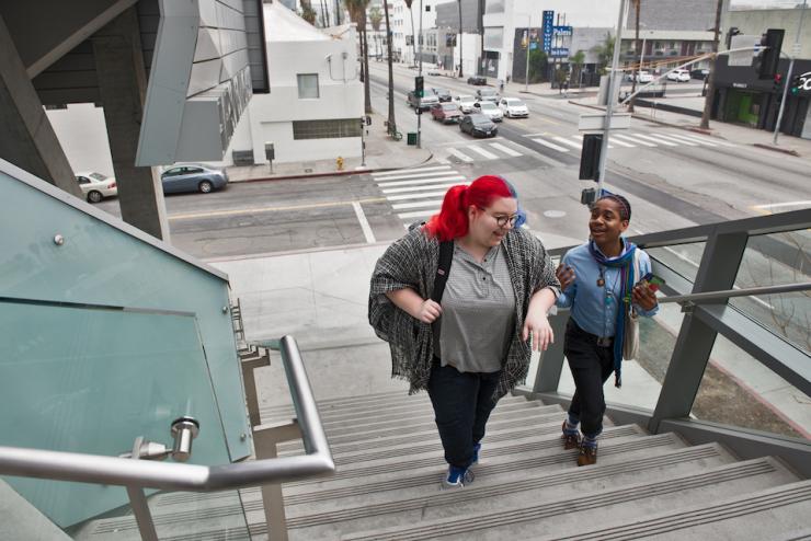 two students talk as they carry bags up the stairs leading into Emerson Los Angeles