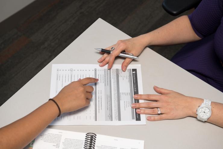 hands pointing at paper with list of courses on it