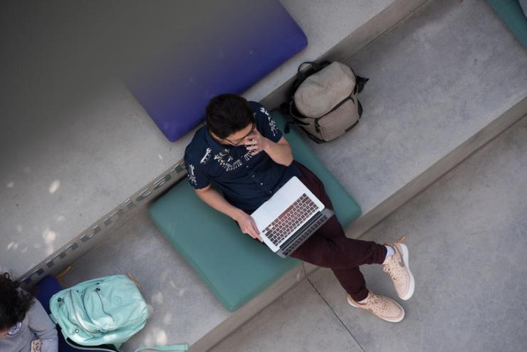 A birds' eye view of a student working on their laptop outdoors