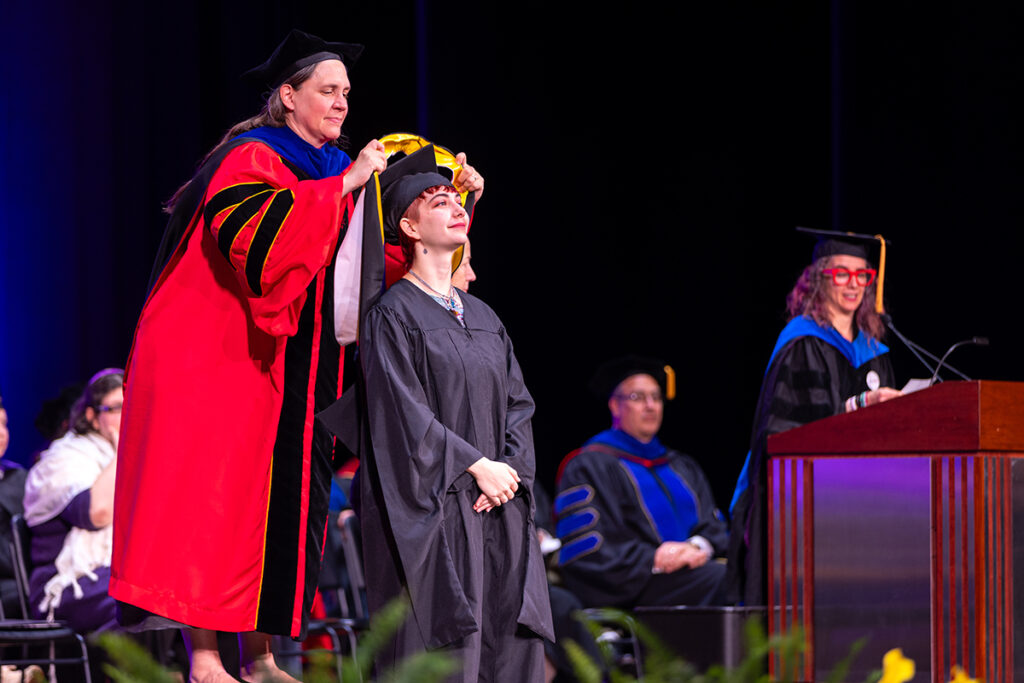 The provost puts a hood over someone's head during the ceremony