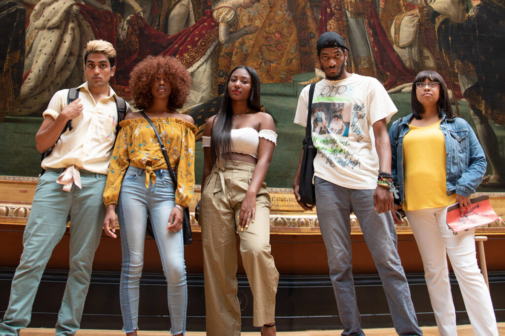 students of color in front of painting in museum|Two people sit on stage during a panel discussion|