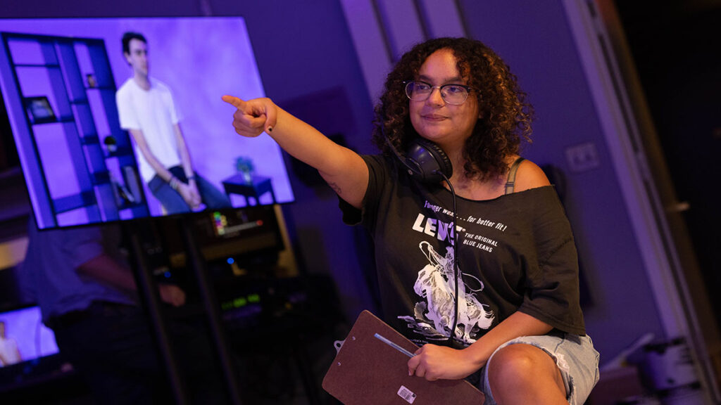 |Behind the scenes of a TV production|A student points while directing a TV production|A student works with lighting equipment|A student looks at a TV camera|Paul Turano teaches analog film to several students