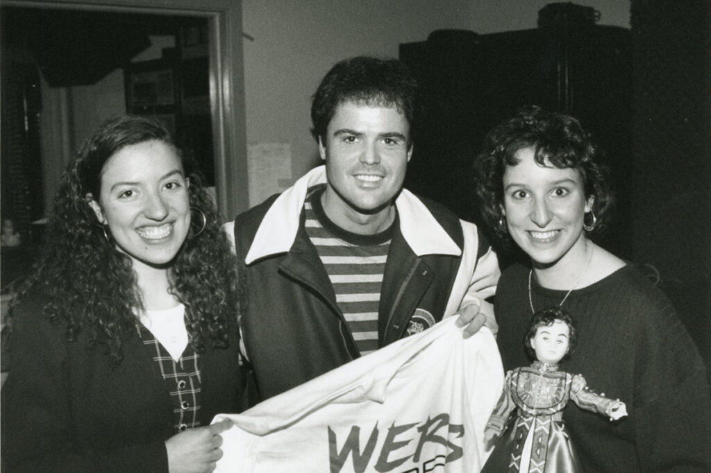 Donny Osmond holds up a WERS shirt with two students next to him|||