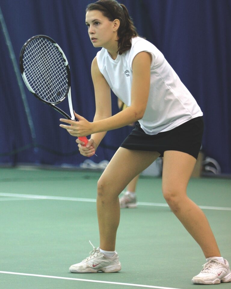 A member of the women's tennis team holds a tennis racquet